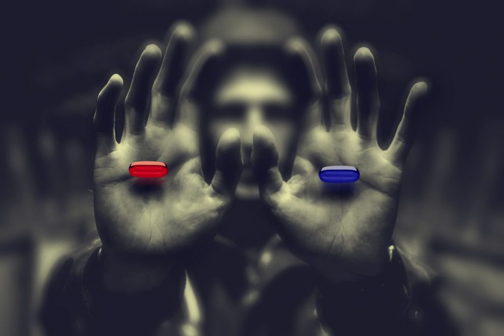 Red pill in one hand, blue pill in other hand