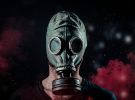 Man wearing gas mask with red smoke in the background.